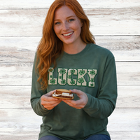 Load image into Gallery viewer, Smiling red-haired woman with long hair eating a s’more on the beach at dusk wearing a green Lucky faux patch long sleeve shirt
