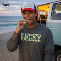 Load image into Gallery viewer, Polynesian man with tattoos is eating smores on the beach at dusk wearing an pepper Comfort Colors Lucky faux patch long sleeve shirt
