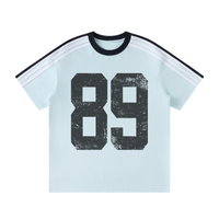 Load image into Gallery viewer, A light blue ringer t-shirt featuring a large distressed black '89' graphic on the front, a black crew neck, and white stripes on the shoulders, displayed on a solid white background.