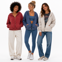 Load image into Gallery viewer, Three women modeling different zip-up hoodies in a studio setting. The woman on the left wears a muted red zip-up hoodie with cream sweatpants.