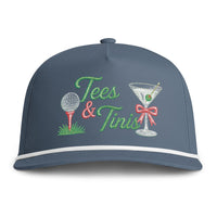 Load image into Gallery viewer, A dark blue baseball cap with embroidered 'Tees &amp; Tinis' text, a golf ball on a tee, and a martini glass with a red bow on the front.