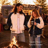 Load image into Gallery viewer, Unisex navy and ivory varsity team jackets worn by man and woman at fall campfire.