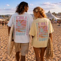 Load image into Gallery viewer, Back of oversized California Surf graphic tee featuring vintage pastel surf artwork, palm trees, mountains, and coastal landscape.