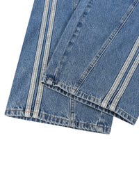 Load image into Gallery viewer, Close-up of blue denim jeans showing the hem and side seam details with contrast stitching, on a plain white background.