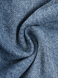 Load image into Gallery viewer, A close-up of blue denim fabric with a textured twill weave, shown in soft folds and swirls.