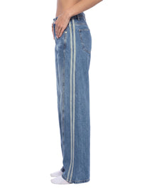 Load image into Gallery viewer, A side-profile view of a person wearing wide-leg blue denim jeans with two vertical light-colored stripes down the outer side of each leg, paired with white socks against a plain white background.